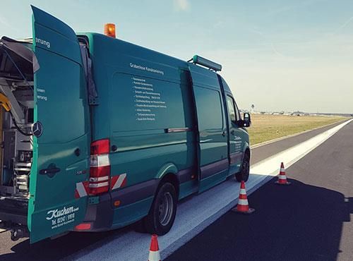 Ein grüner Lieferwagen steht mit offenen Türen am Straßenrand.