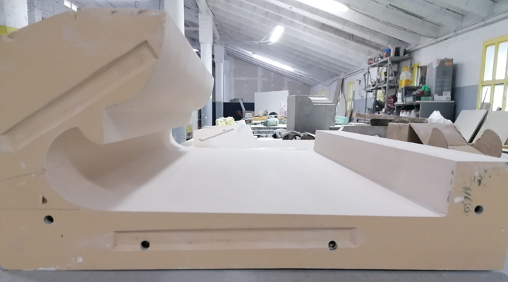 Gran molde de color canela en un taller, posiblemente para fabricación, con herramientas y un fondo desordenado.