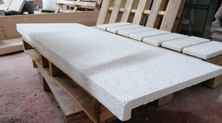 Una gran encimera de piedra blanca y varios azulejos a juego están dispuestos sobre un palé de madera.