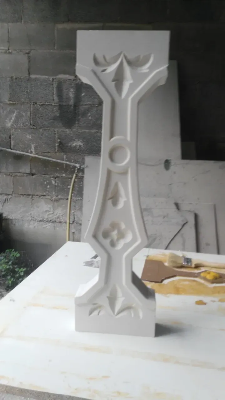 Pilar de piedra tallada en color blanco con detalles decorativos florales y geométricos.
