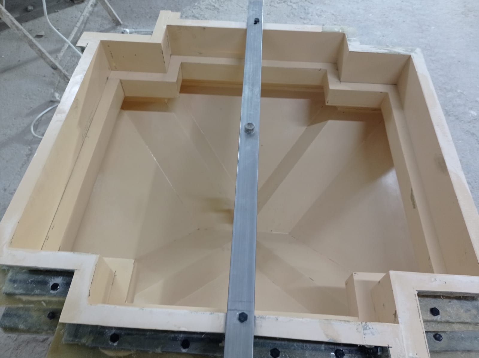 Molde de madera con carril guía metálico en su interior, probablemente para construcción.