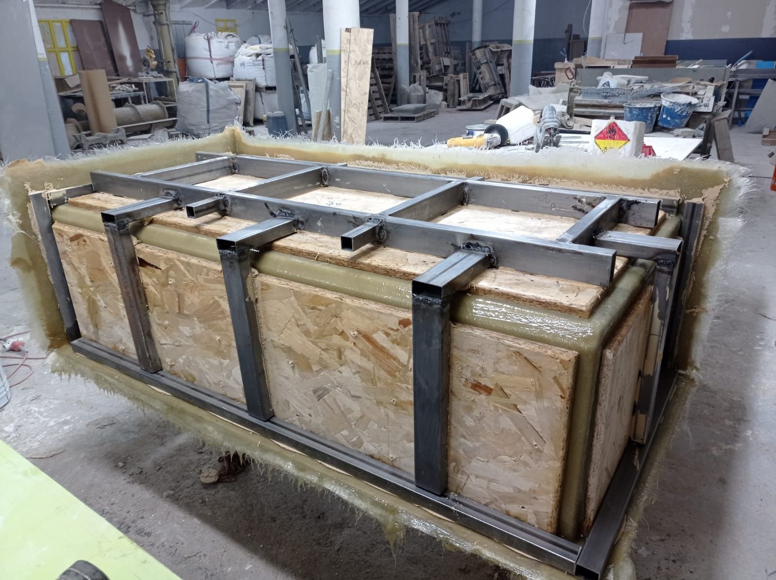 Caja de madera con marco de metal, posiblemente un molde, en un entorno de taller.