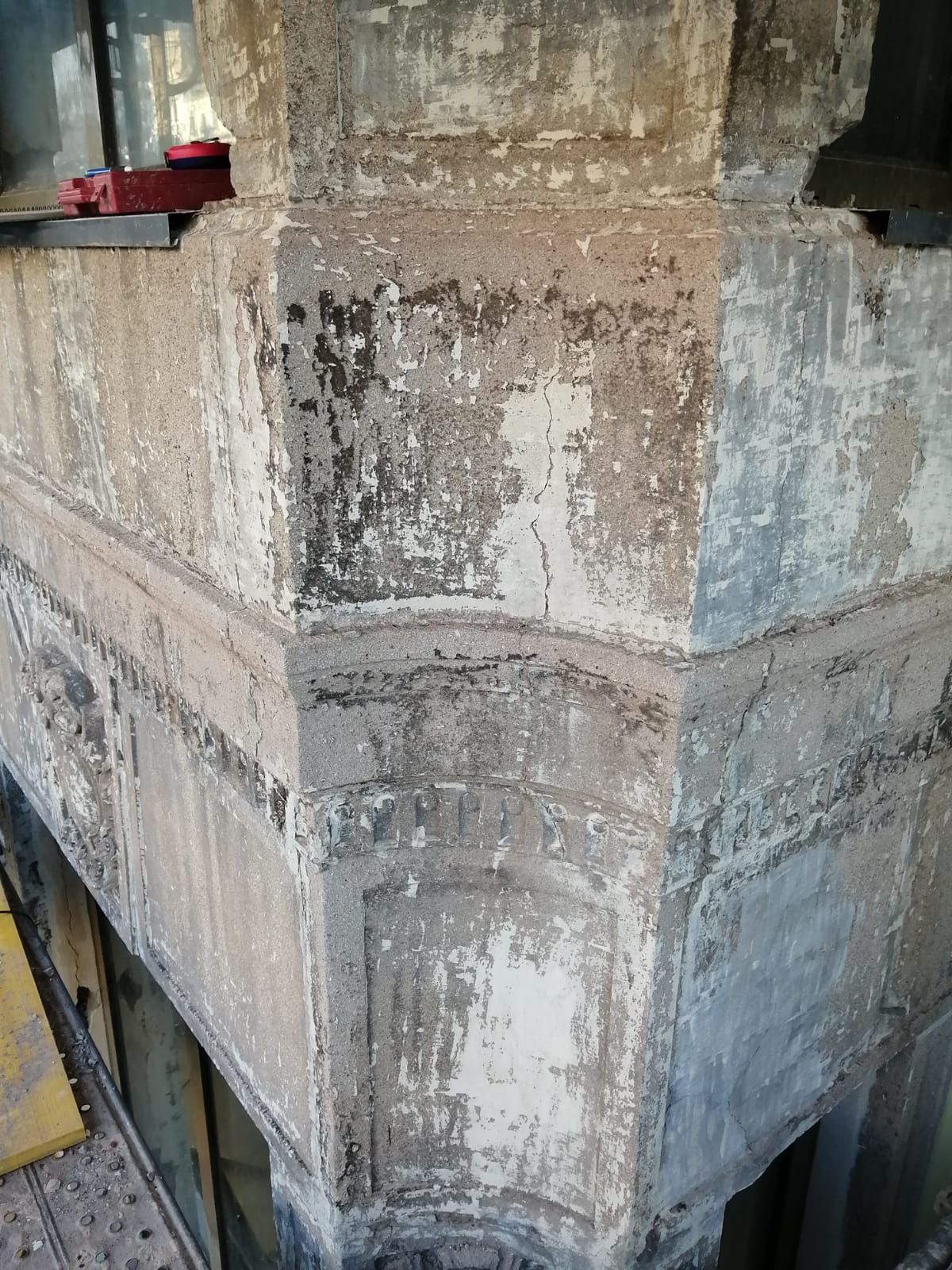 Esquina de un edificio de piedra con pintura descascarada.