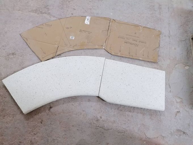 Patrón de cartón color canela junto a secciones de espuma blanca curvada sobre una superficie de hormigón.