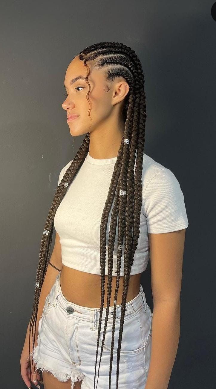 Mujer joven con cabello largo trenzado, con un top blanco y pantalones cortos.