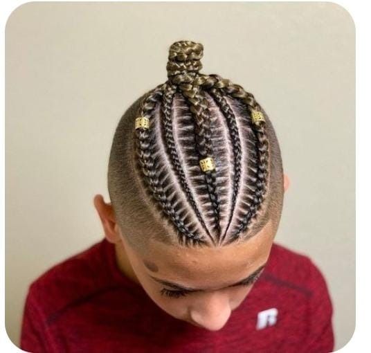 Niño con peinado trenzado, lados rapados y detalles dorados.