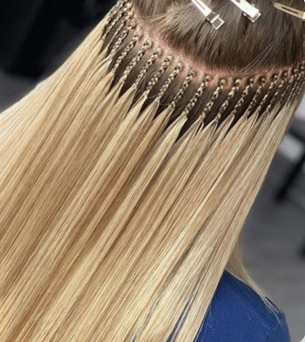 Extensiones de cabello rubio con pequeñas trenzas unidas al cabello natural, sujetadas con clips.