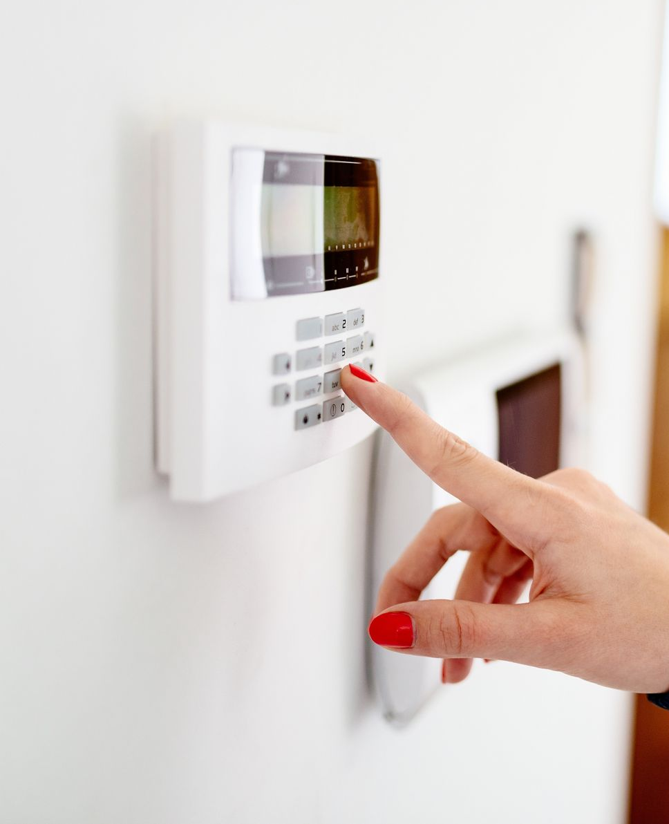 Appuyer sur le bouton d'un clavier d'alarme domestique blanc avec petit écran.