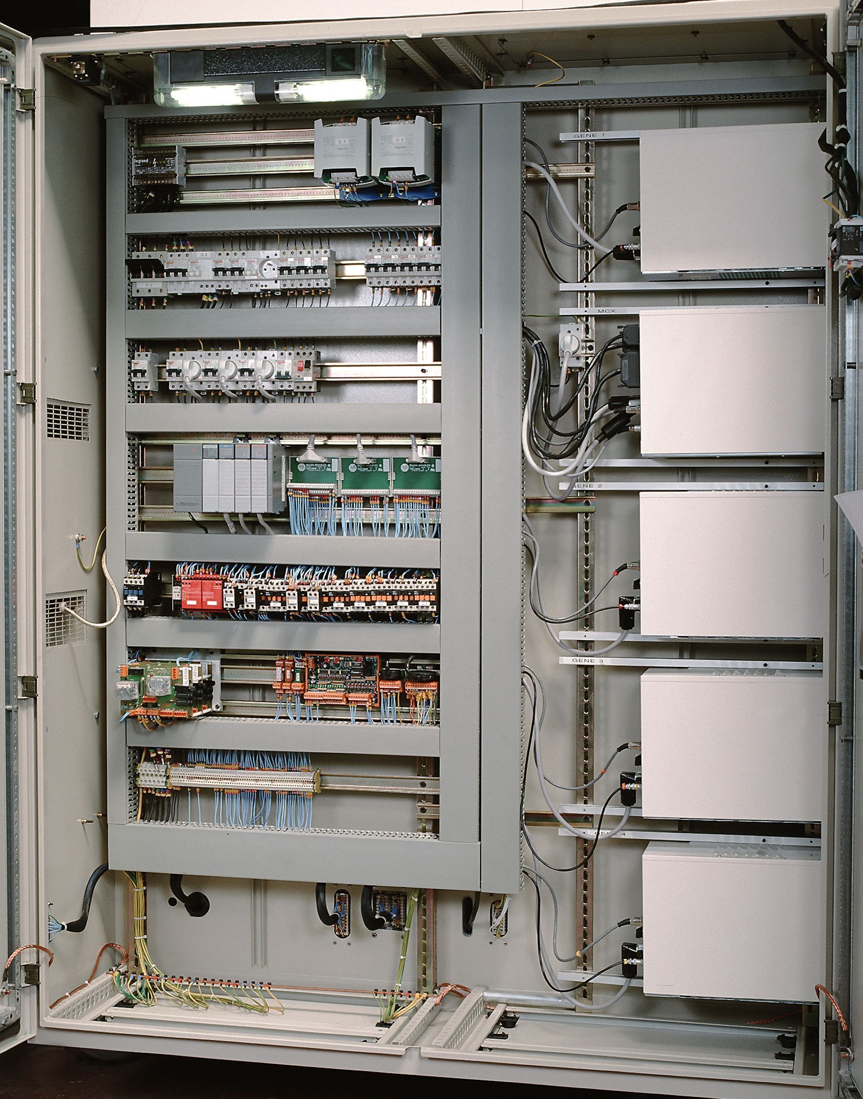 Panneau de commande électrique ouvert avec cartes de circuits imprimés, câblage et composants à l'intérieur d'une armoire.