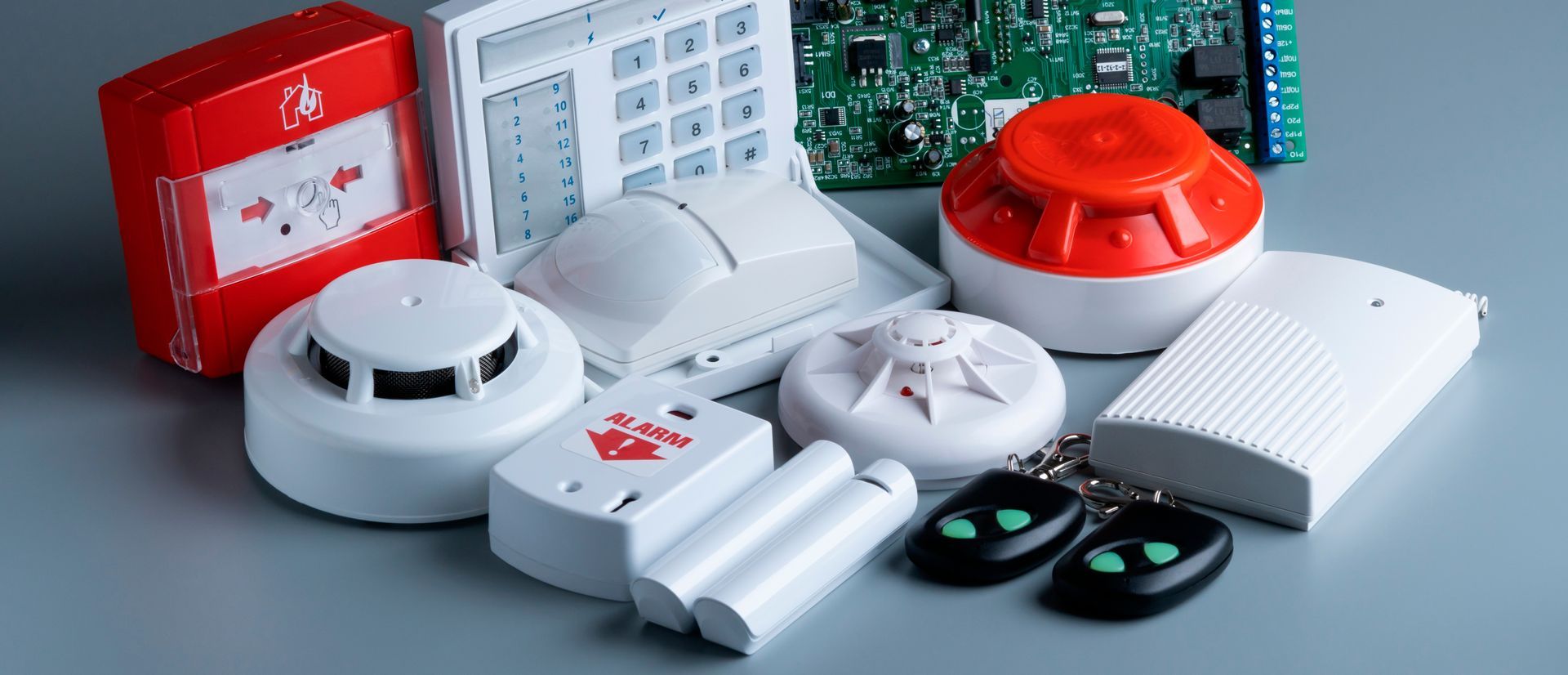 Divers dispositifs d'alarme et détecteurs domestiques blancs et rouges sur une table.