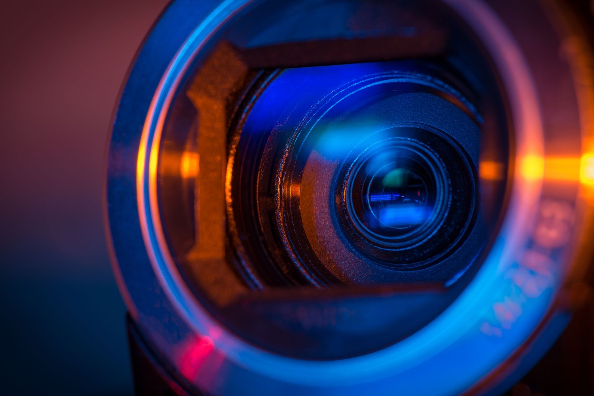 Gros plan sur un objectif d'appareil photo avec des reflets bleus et orange.