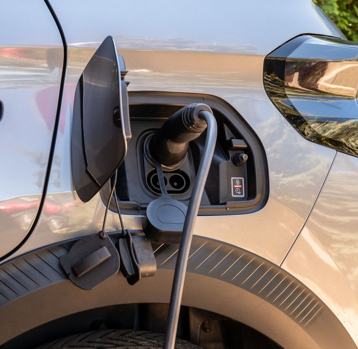 Port de recharge pour véhicule électrique avec câble branché sur une voiture argentée.