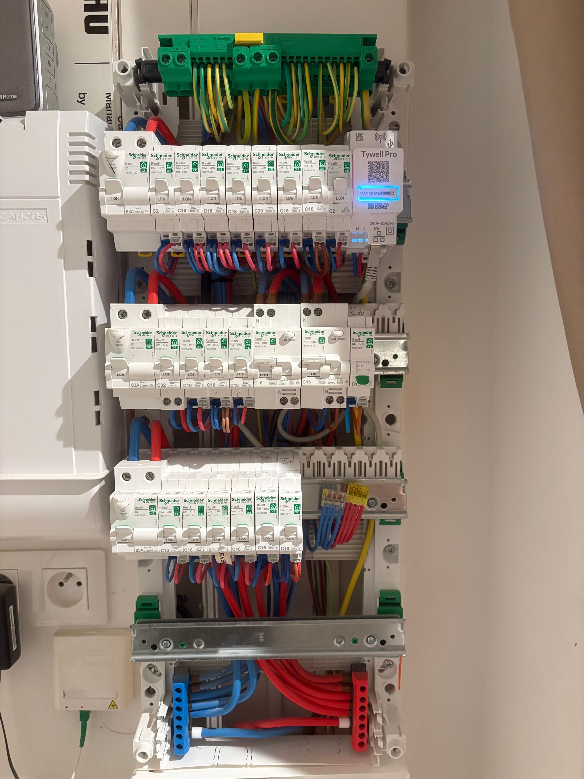 Tableau de commande électrique avec rangées de disjoncteurs et câblage à code couleur dans une armoire.