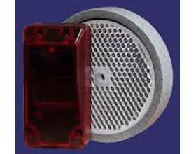 Una caja roja está al lado de un reflector blanco sobre un fondo azul.