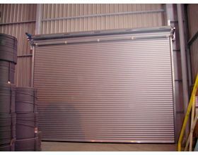 Una gran puerta de garaje de metal está abierta en un almacén.