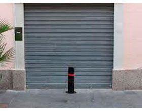 Una puerta de garaje gris con un poste negro delante de ella.