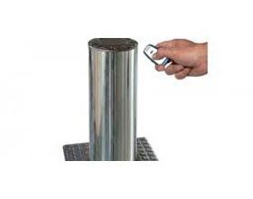 Una persona sostiene un control remoto al lado de un poste de acero inoxidable.