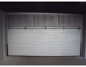 Una puerta de garaje blanca está abierta en una habitación oscura.