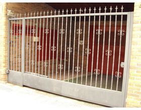 Una puerta de hierro forjado se encuentra frente a un edificio de ladrillo.