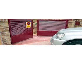 Un coche está aparcado delante de una puerta roja.