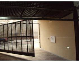 Una valla está abierta y hay un coche aparcado detrás de ella.