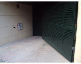 Un garaje vacío con una puerta verde y una pared blanca.