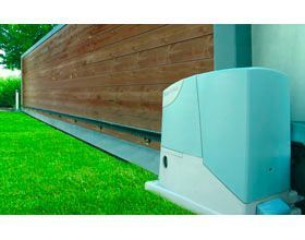 Un motor de puerta corrediza está fijado al costado de un edificio de madera.