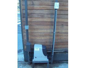 Un motor de puerta corrediza está sentado al lado de una pared de madera.