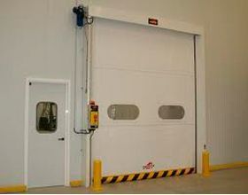 Una puerta de garaje blanca está abierta en un almacén al lado de una puerta.