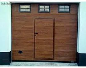 Una puerta de garaje de madera con tres ventanas y una puerta.