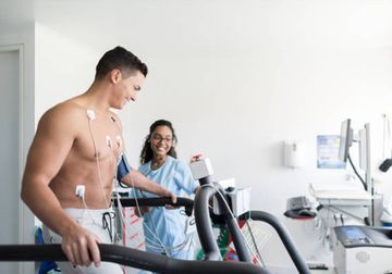 Un hombre camina en una cinta de correr en un hospital mientras una enfermera lo observa.