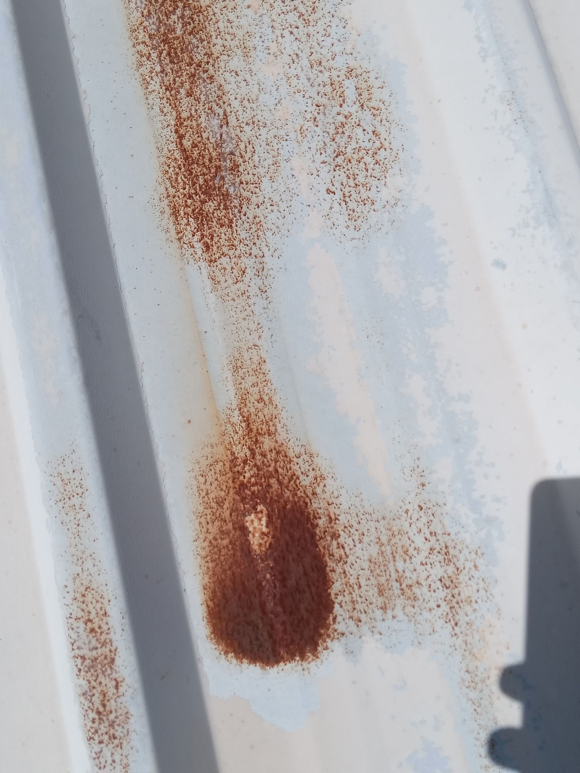 Taches de rouille sur tôle ondulée blanche.