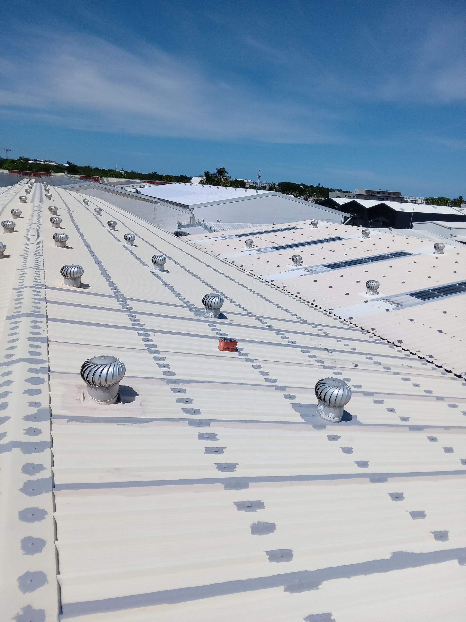 Toit industriel blanc avec plusieurs conduits d'aération rotatifs.