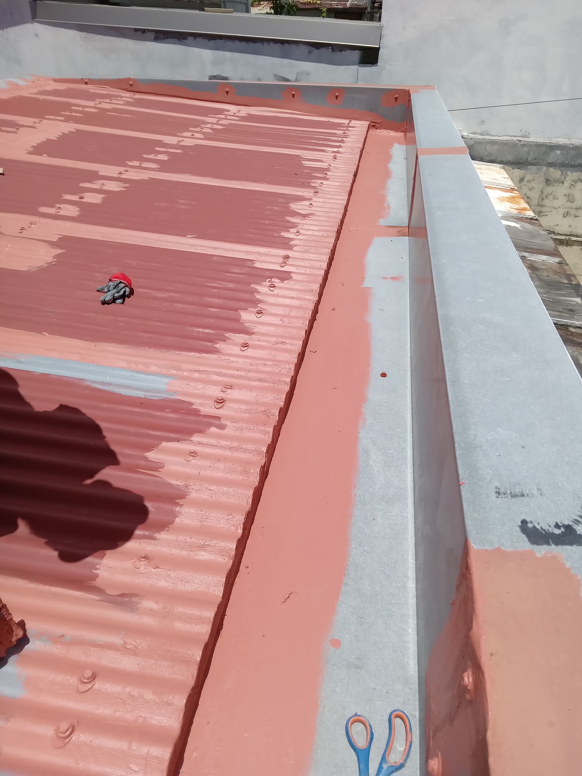 Toiture en cours de peinture brun rougeâtre.