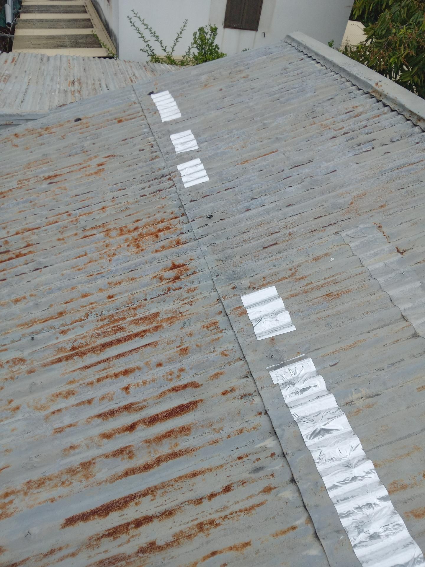 Toit en tôle ondulée rouillée avec des plaques argentées.