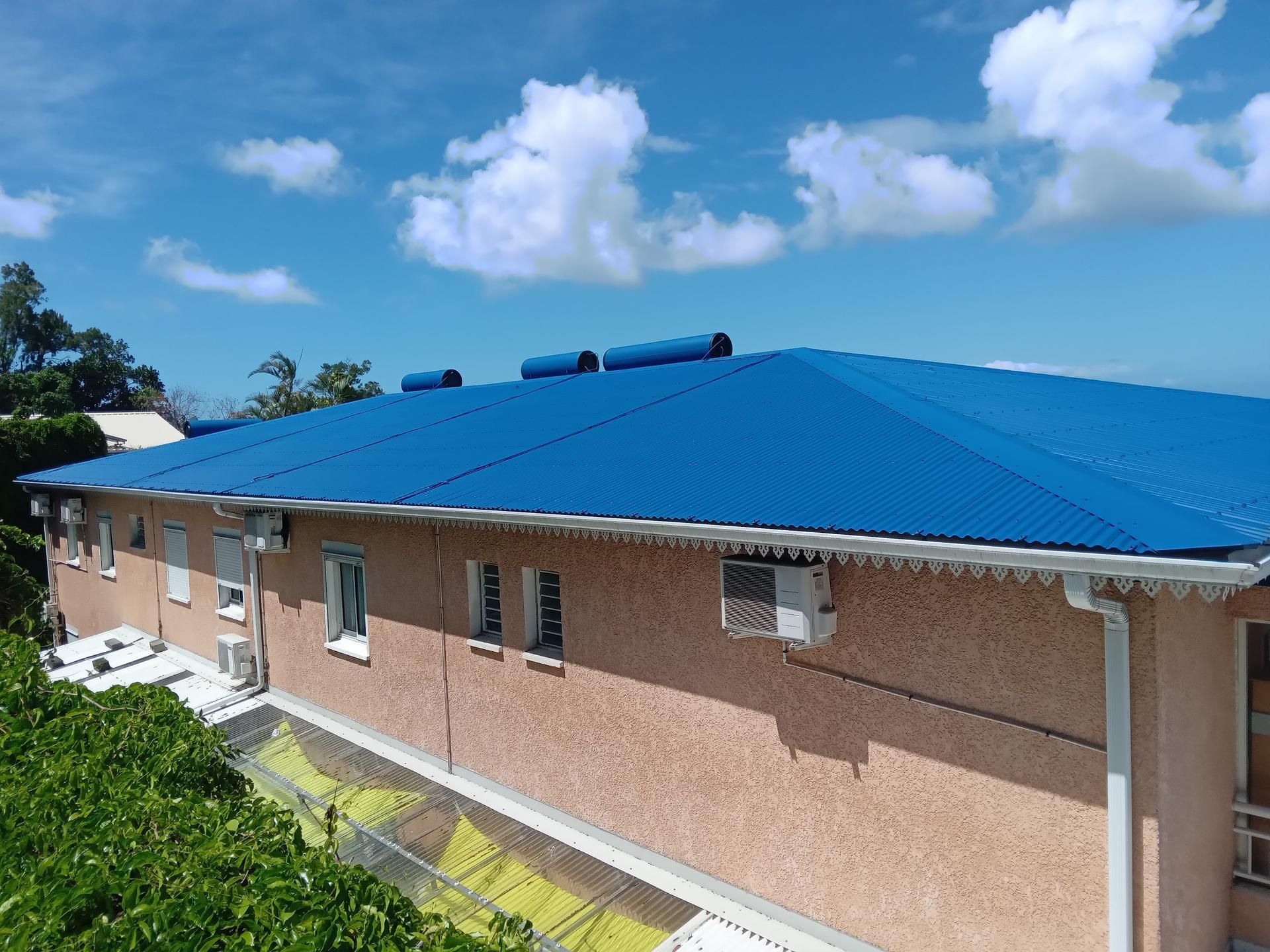 Toiture métallique bleue sur un bâtiment beige.