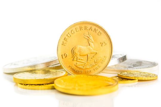 Una moneda de oro está encima de una pila de monedas de plata.