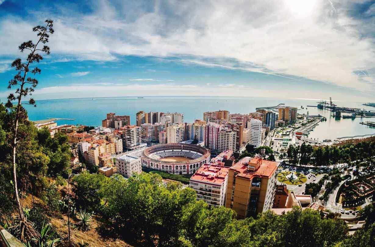 Una vista aérea de una ciudad con un estadio en primer plano y el océano en el fondo.