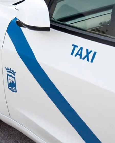 Un taxi blanco con una franja azul en el costado.