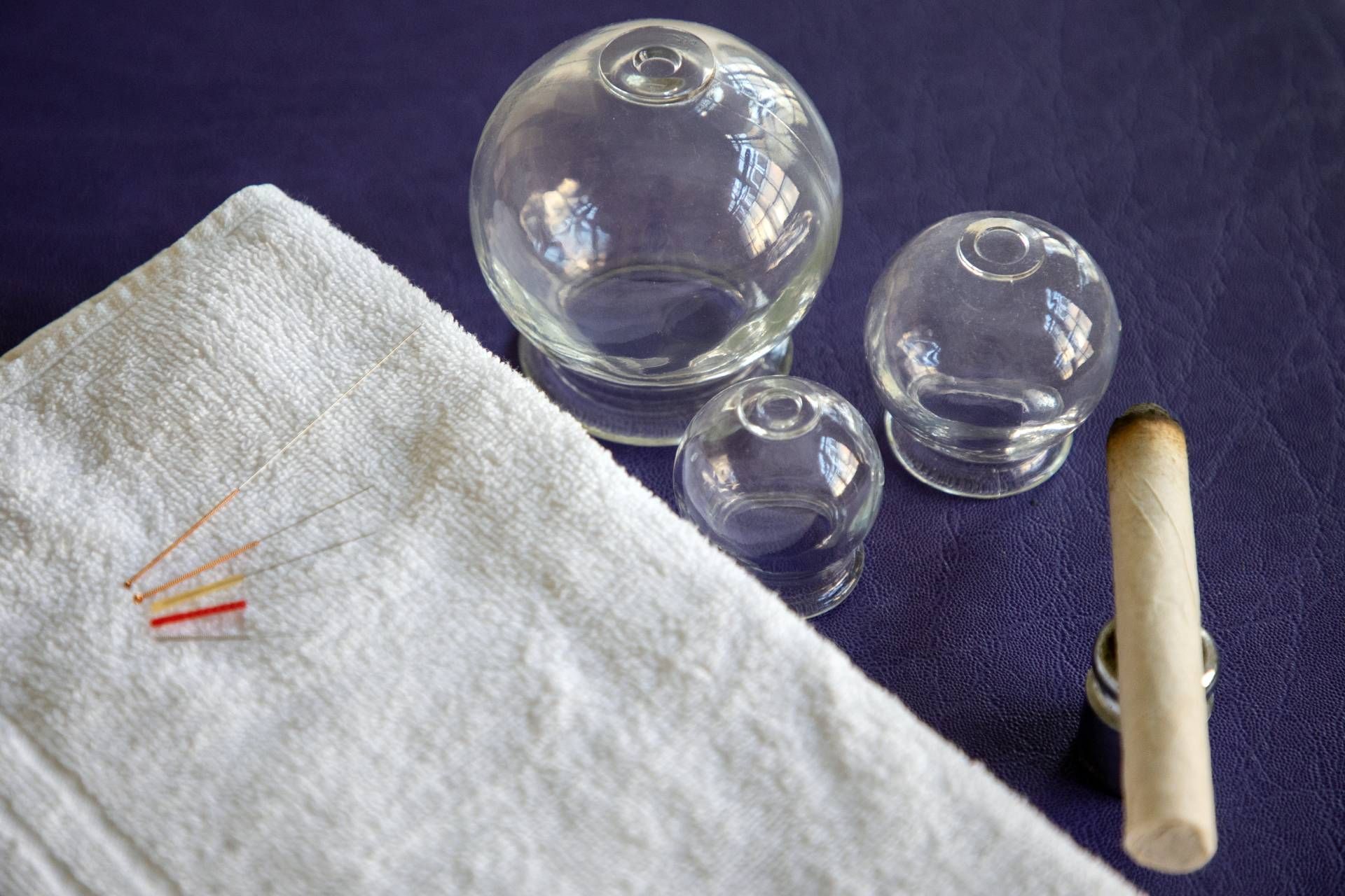 Massagetherapieraum mit blauem Tisch, weissem Schreibtisch, Schränken und einer Tür.