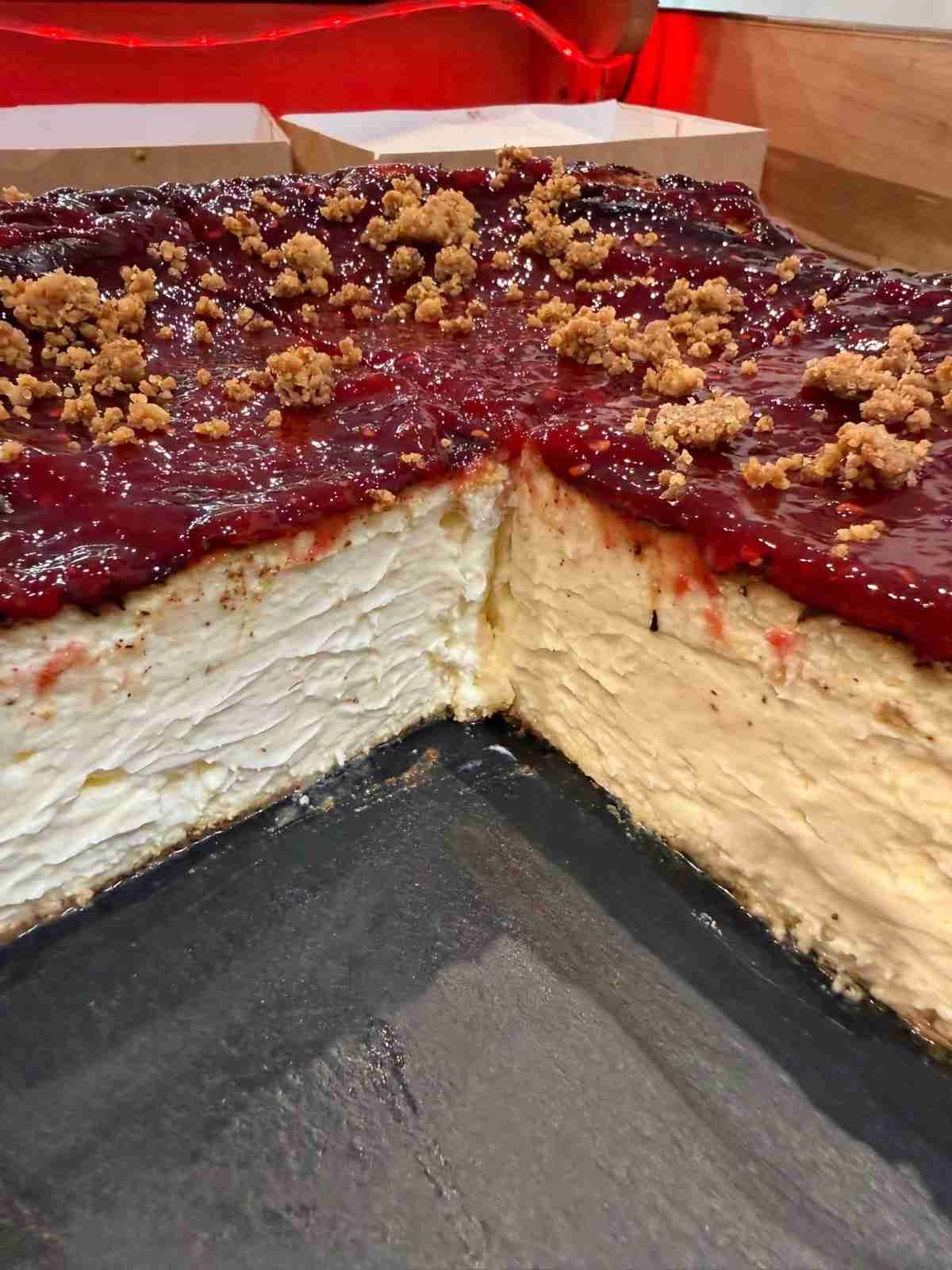 Primer plano de un postre en capas con cobertura de frutos rojos y streusel desmigado en una bandeja