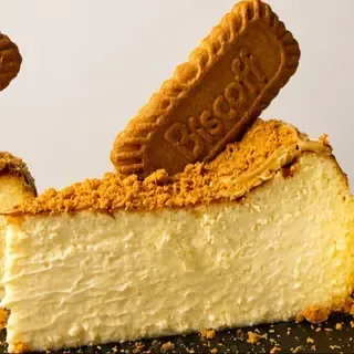 Porción de tarta de queso cremosa cubierta con una galleta Biscoff y migas de galleta triturada