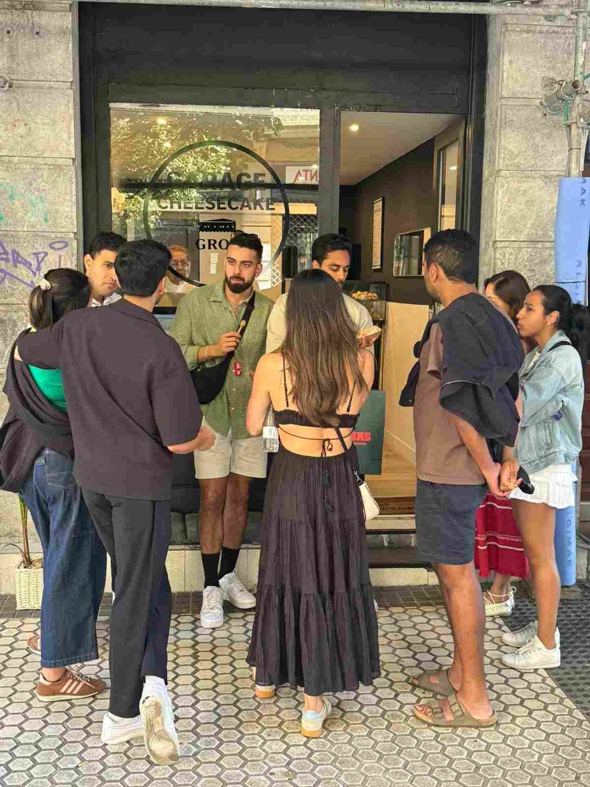 Un grupo de personas reunidas frente a la entrada de un edificio, conversando en un pequeño círculo.
