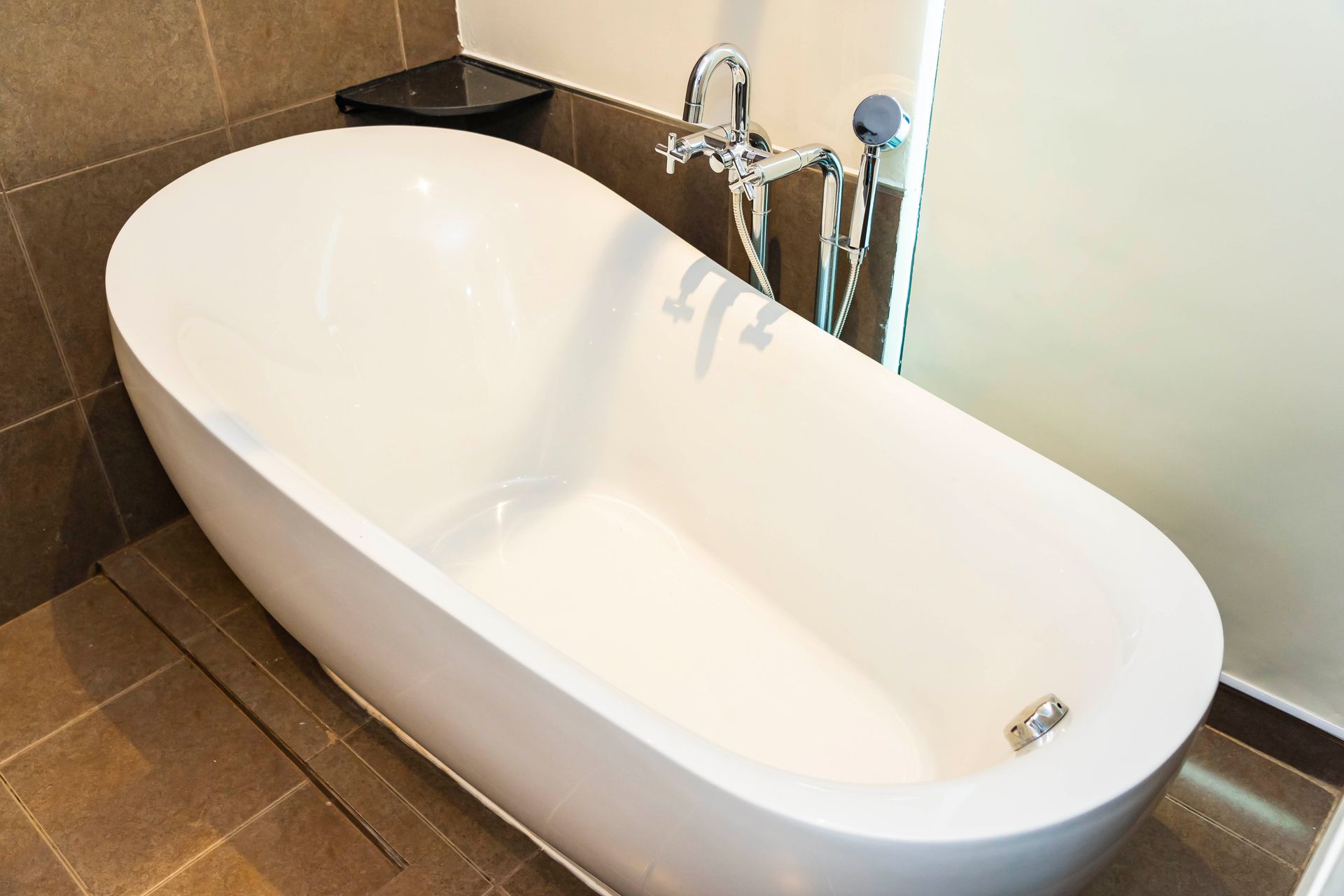 In einem Badezimmer steht eine weiße Badewanne neben einer Dusche.