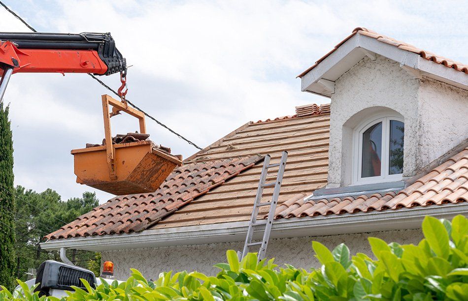 Grutier apportant de nouvelles tuiles aux employés travaillant sur la toiture d'une maison