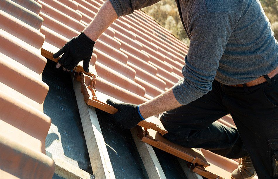 Ouvrier du bâtiment posant de nouvelles tuiles sur une toiture