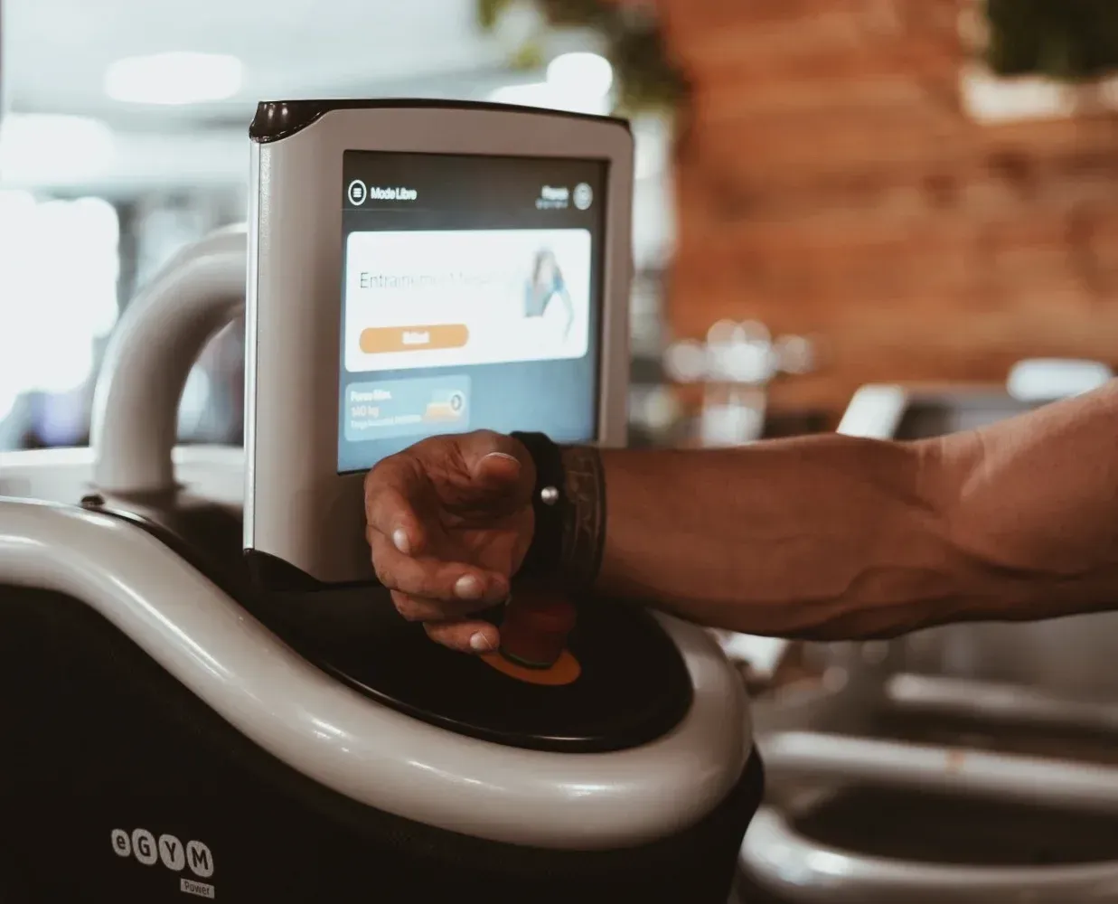 Personne avec un bracelet connecté devant un écran affichant le logiciel eGym pour collecter des données.