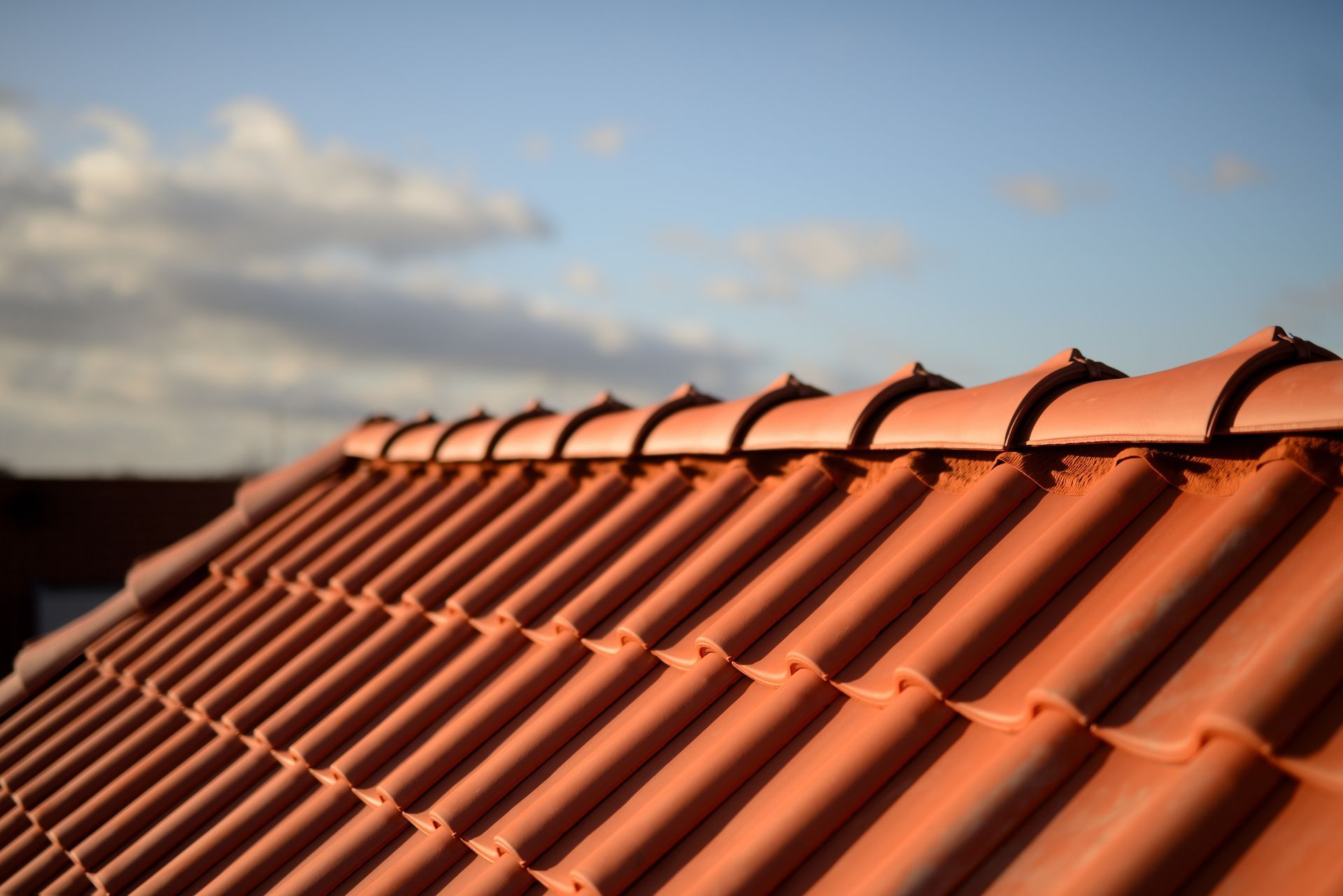 Tuiles en terre cuite rouges sur un ciel bleu avec des nuages.