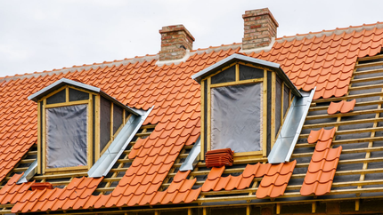Toiture en tuiles rouges, avec deux lucarnes et deux cheminées. Réfection partielle en cours.
