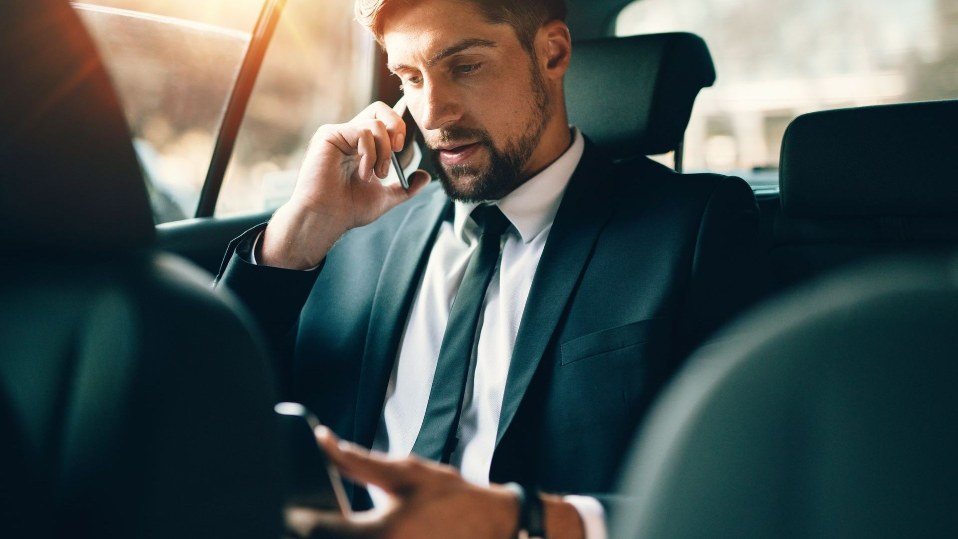 Un homme en costume à l'arrière d'un taxi.